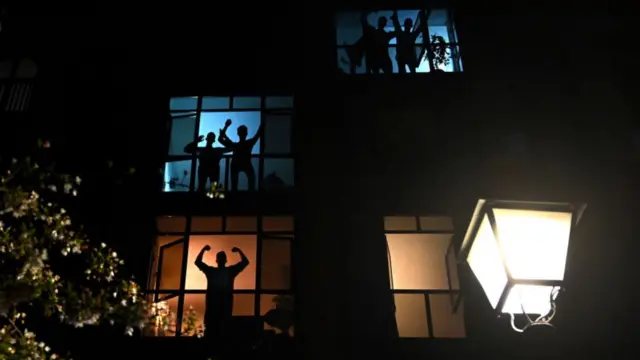 People in apartment windows cheering for Spain's healthcare workers on 28 March 2020