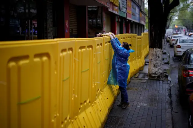 A person passes food over a barricade in Wuhan