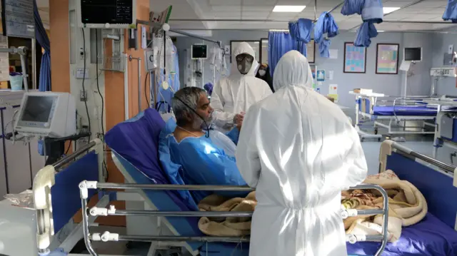 Staff at a hospital in Tehran, Iran, take care of a patient infected by coronavirus, 2 March 2020