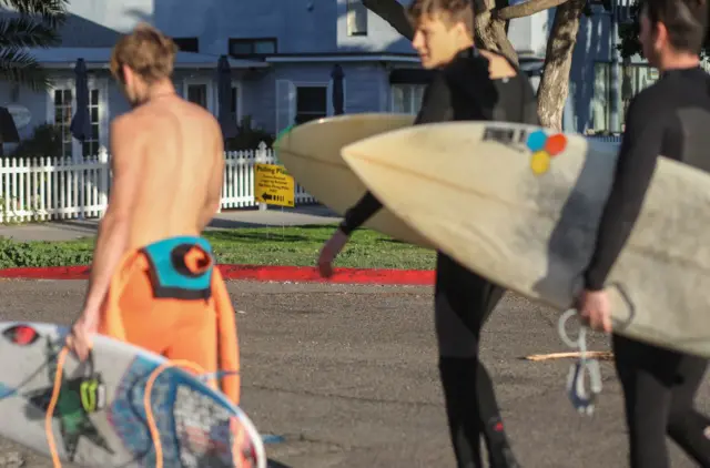 Surfers walk by a polling place sign in San Diego