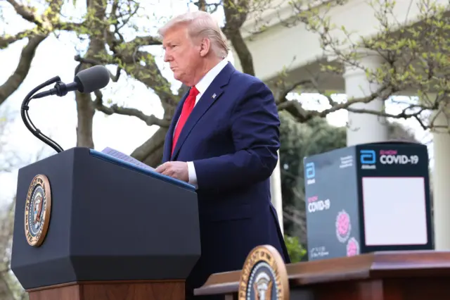 As a new COVID-19 test kit developed by Abbott Labs is placed on a table, U.S. President Donald Trump speaks during the daily coronavirus briefing at the Rose Garden of the White House on 30 March, 2020 in Washington, DC