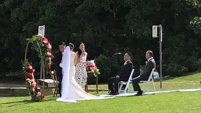 A bride and groom with a celebrant and two witnesses beside Sydney's harbour on Sunday