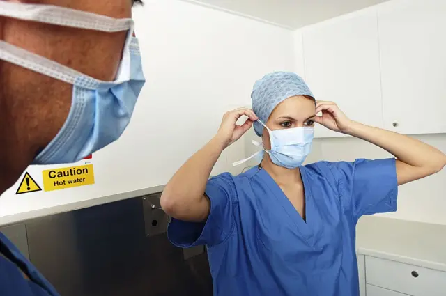 Female surgeon putting on surgical face mask before operation