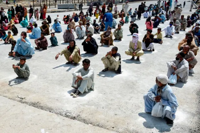 People waiting to receive food in Karachi amid a lockdown