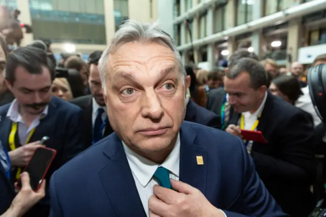 Viktor Orban walking through a crowd of reporters in Brussels