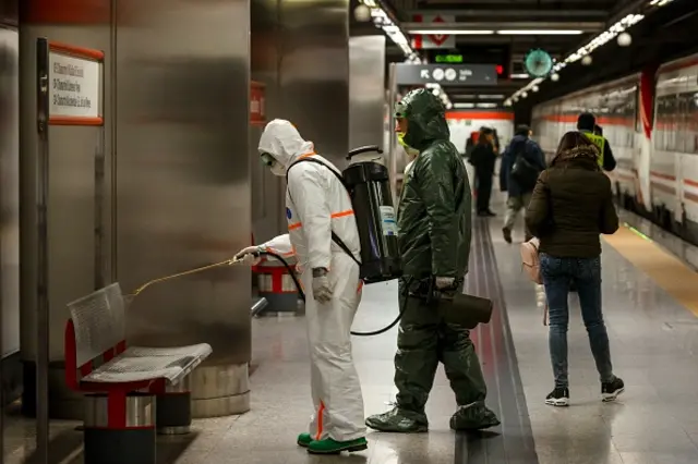 Men in hazmat suits disinfect a subway in Madrid