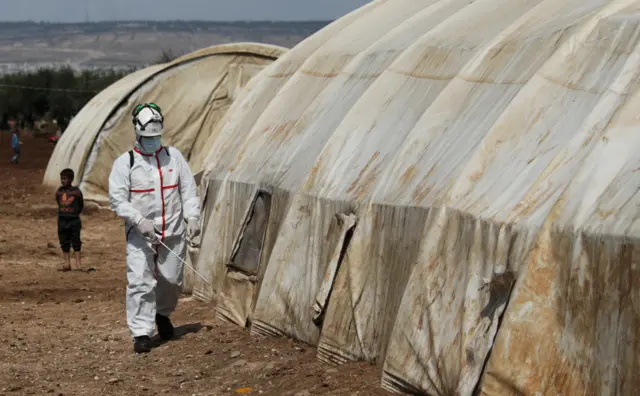 A civil defence volunteer sprays a tent with disinfectant at the Bab al-Nour camp for displaced people in Azaz, Syria, to prevent the spread of Covid-19 (26 March 2020)