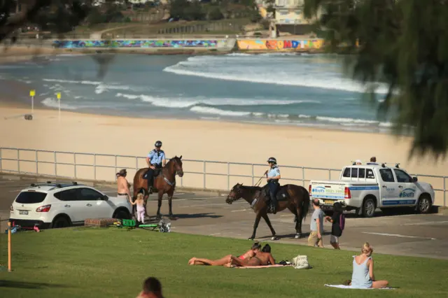 Two police officers on horseback speak to people on Bondi Beach in Sydney