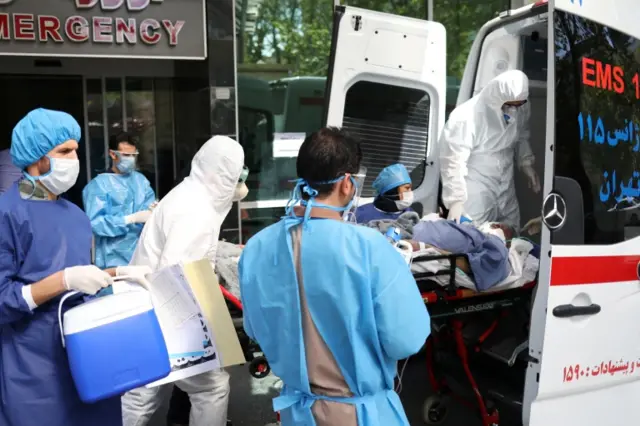 Medics wearing protective suits transfer a patient with Covid-19 to Masih Daneshvari Hospital, in Tehran, Iran (30 March 2020)