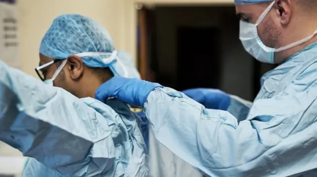 Doctors putting on protective gear in a hospital