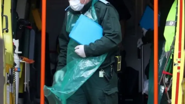 A paramedic wearing an apron and face mask