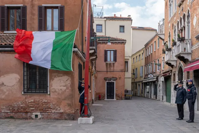 Italian police salute the flag, flown at half mast to honour the dead