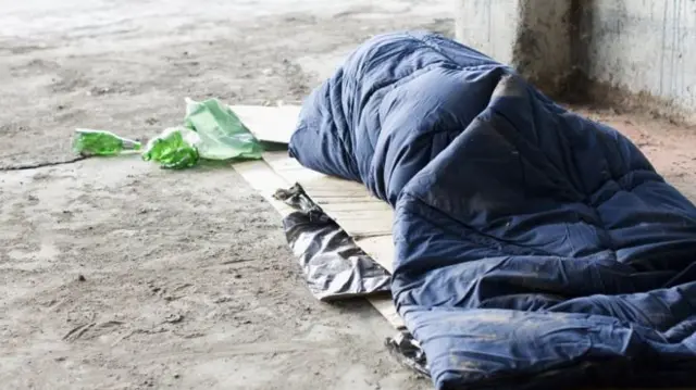 A homeless person in a sleeping bag