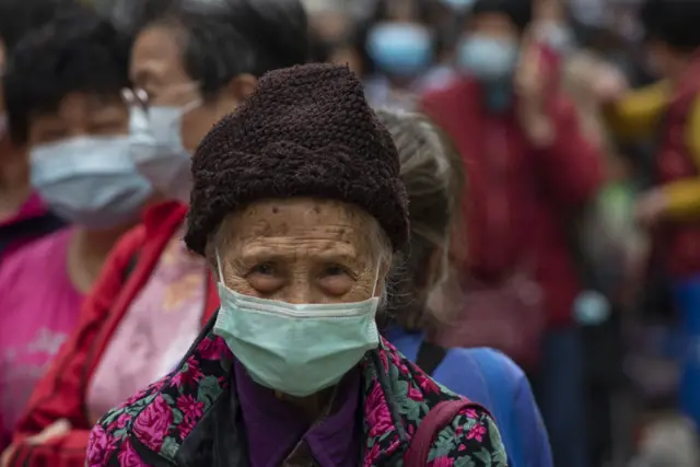 An elderly resident waits in line to receive hygiene goods in an impoverished district of Kowloon, Sham Shui Po in Hong Kong on March 12, 2020.