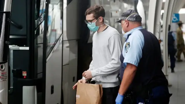 A police officer escorting a returned traveller to his hotel quarantine