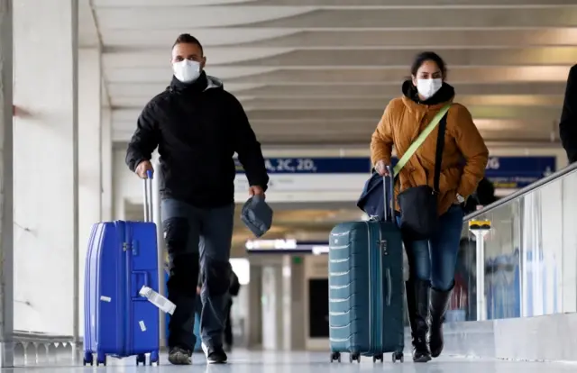 People wearing protective face masks arrived at Charles de Gaulle airport near Paris