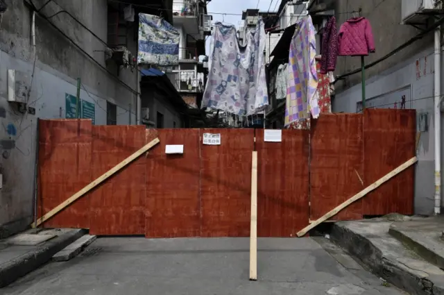 Laundry is put to dry above boards blocking an entrance to a residential area in Wuhan. Photo: 4 March 2020