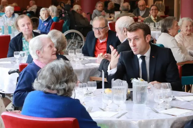 Emmanuel Macron gestures as he eats with the residents during a visit to an EHPAD (Housing Establishment for Dependant Elderly People), in the 13th arrondissement of Paris