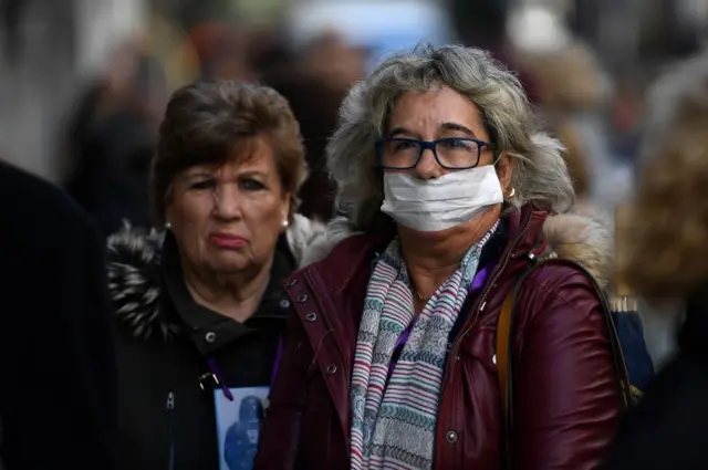 A woman wearing a protective mask queues with other worshippers outside the Jesus of Medinaceli church in Madrid