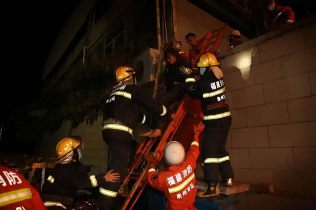 Rescuers carry out an injured woman from the rubble