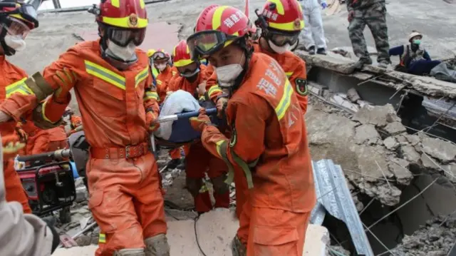 A man (C) is rescued from the rubble of a collapsed hotel in Quanzhou on March 8, 2020