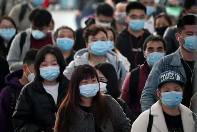 Passengers wearing face masks arrive at Changsha railway station in Changsha, the capital of Hunan province on March 8, 2020.