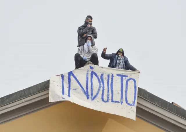 Detainees display a banner reading "Indulto", Italian for pardon, as they protest on the roofs of the San Vittore prison in Milan