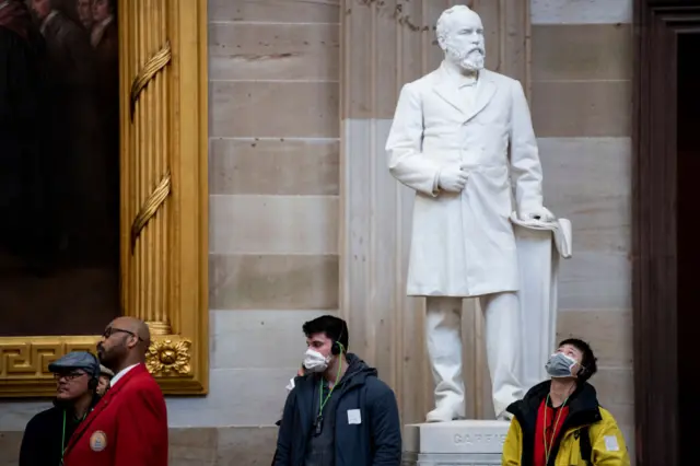 Tourists wearing protective masks tour the US Capitol Rotunda