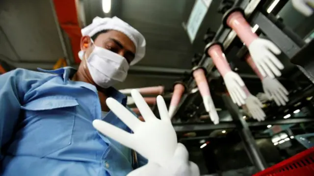 A worker inspects a glove at the factory of Top Glove in Kelang, outside Kuala Lumpur September 25, 2009