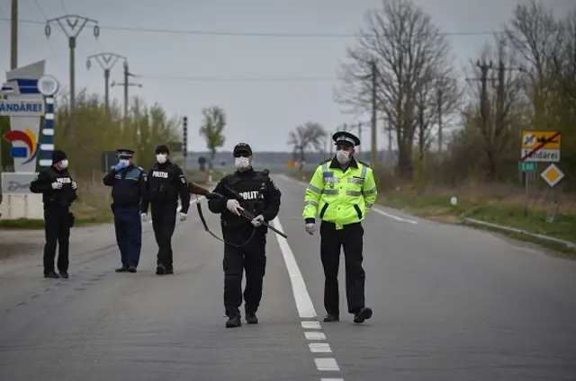 Romanian policemen stand at a makeshift checkpoint at the entrance of the town of Tandarei, where a complete lockdown has been in place