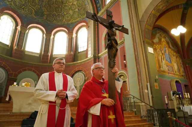 Berlin Archbishop Heiner Koch (R) and Monsignor Hansjoerg Guenther rehearse the veneration of the cross for the Good Friday liturgy that will be broadcast live from Saint Joseph Church