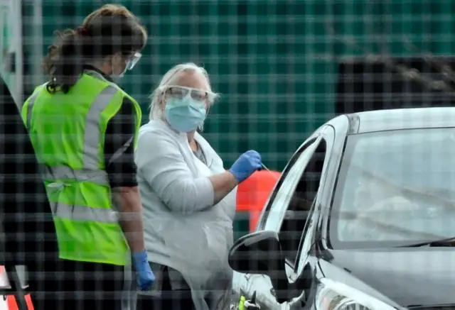 A worker wears a face mask as she tests staff for coronavirus