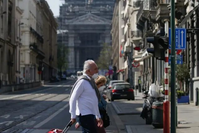 A couple wearing a mask cross the street in Belgium