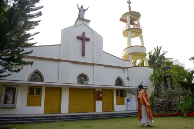 Roman Catholic Priest, Father P.Gnana Reddy, holds palm fronds as he walks alone prior to celebrates a private mass on a Palm Sunday event outside the Saint Joseph's Church during a 21-day government-imposed nationwide lockdown as a preventive measure against the COVID-19 coronavirus