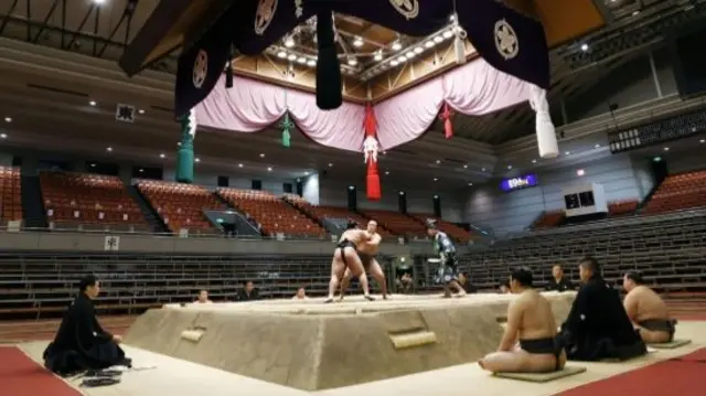 Two sumo wrestlers take part in the Spring Grand Sumo Tournament in front of empty seats