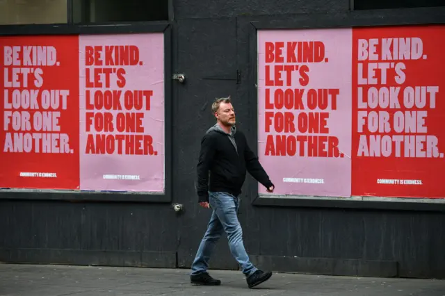 Members of the public walk past new posters placed around the city center on April 9, 2020 in Glasgow, Scotland. There have been around 60,000 reported cases of coronavirus (COVID-19) in the United Kingdom and 7,000 deaths. The country is in its third week of lockdown measures aimed at slowing the spread of the virus. (Photo by Jeff J Mitchell/Getty Images)