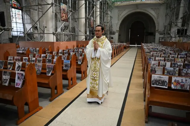 Father Mark de Leon begins an Easter mass in Angeles City, Pampanga in the Philippines with photos of parishioners taped on church pews