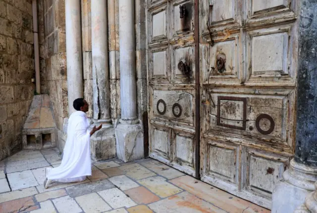 A man prays in front of the closed Church of the Holy Sepulchre before the start of the Easter Sunday service