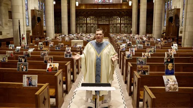 Rev Brian X Needles live-streams Easter Mass to pictures of parishioners attached to pews at Our Lady of Sorrows Catholic Church in the US state of New Jersey