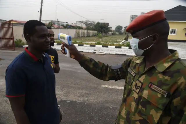 A soldier checks the body temperature of a civilian in Lagos, Nigeria