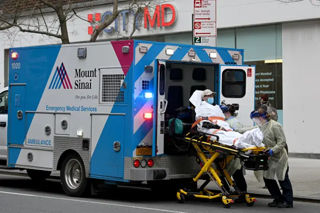 Medical workers load a Covid-19 patient into an ambulance in New York