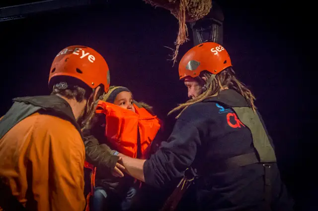 A young child is rescued from a boat by the crew of the Alan Kurdi rescue ship