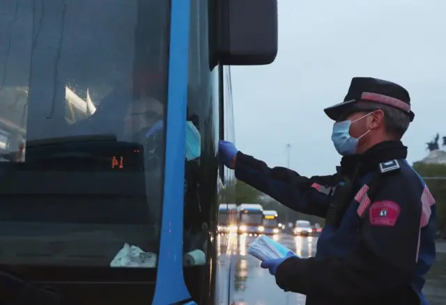 A municipal police officer gives masks to a bus driver