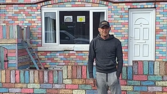 Craig outside his rainbow-coloured house