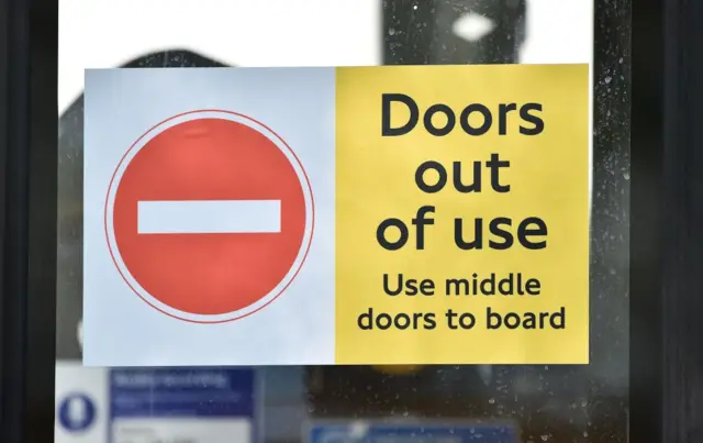 A no-entry sign on the doors of a London bus during the coronavirus pandemic; it says use middle doors instead