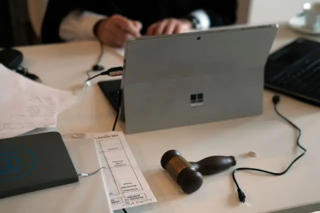 Equipment being used by a remote judge including a tablet computer, documents and a gavel