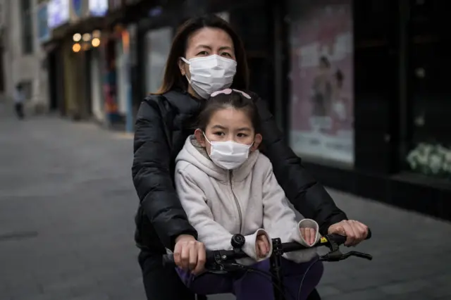 The mother wear a mask while ride bike with her daughter on April 11, 2020 in Wuhan