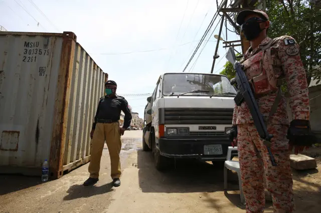 Pakistan security officials block a road during full lockdown in Karachi of Sindh province