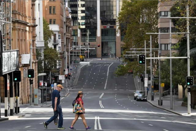 A man and woman walk across an empty road in Sydney's centre during the coronavirus pandemic