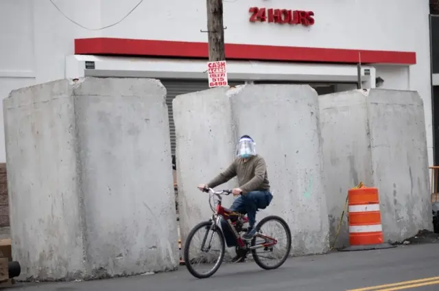 A man cycles in Queens, New York while wearing a mask